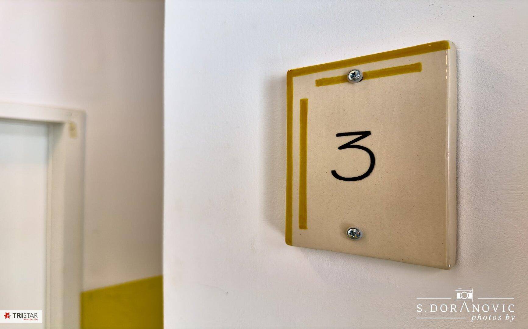 Apartmentnummer 3 an der Wand im Flur, gut sichtbar und klar gekennzeichnet.