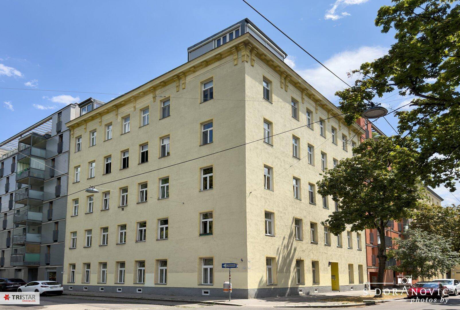Eckgebäude mit mehreren Stockwerken und klassischer Fassade an einer städtischen Straße.