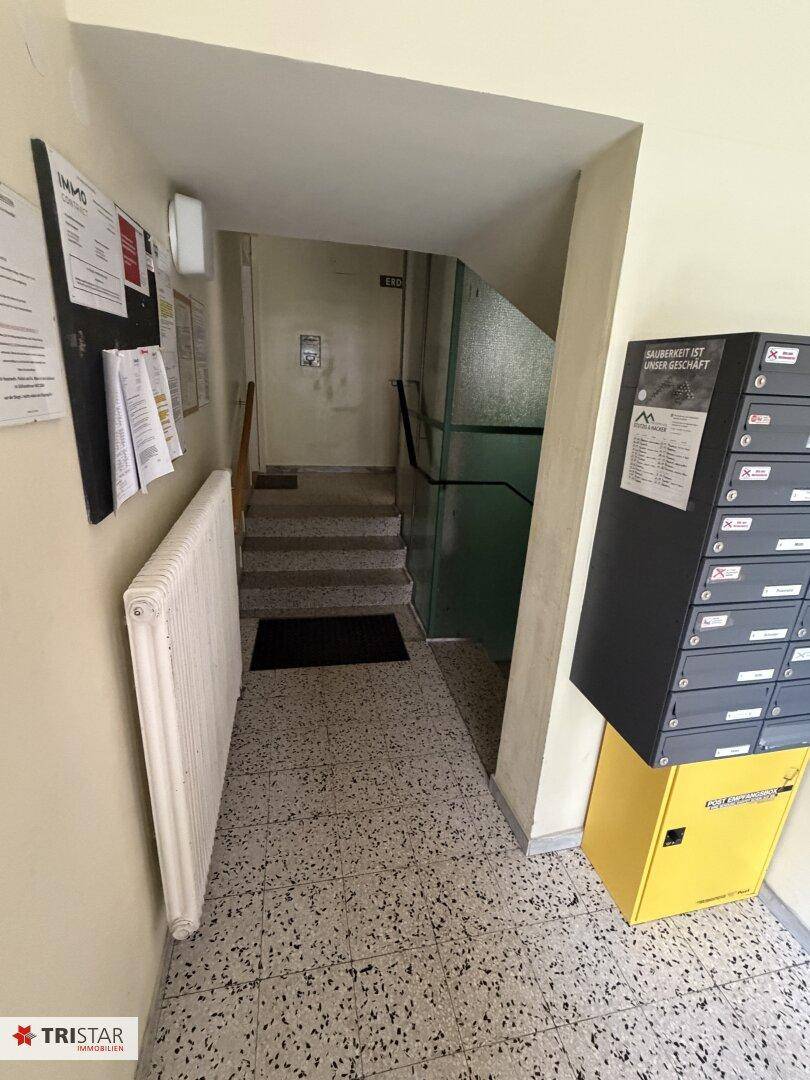 Gemeinschaftlicher Flur mit Briefkästen, Heizkörper und Treppenaufgang, funktional und hell.