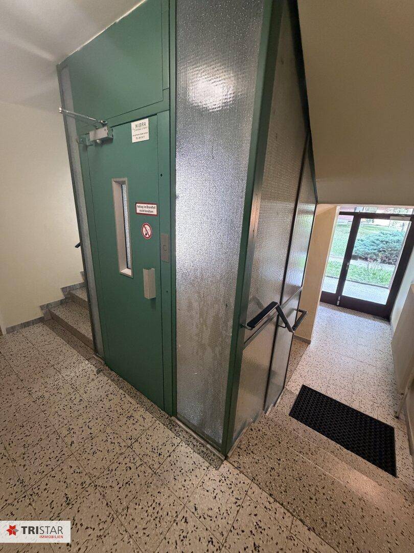 Gemeinschaftlicher Flur mit Aufzug und Treppenhaus in einem Wohngebäude, gut zugänglich.