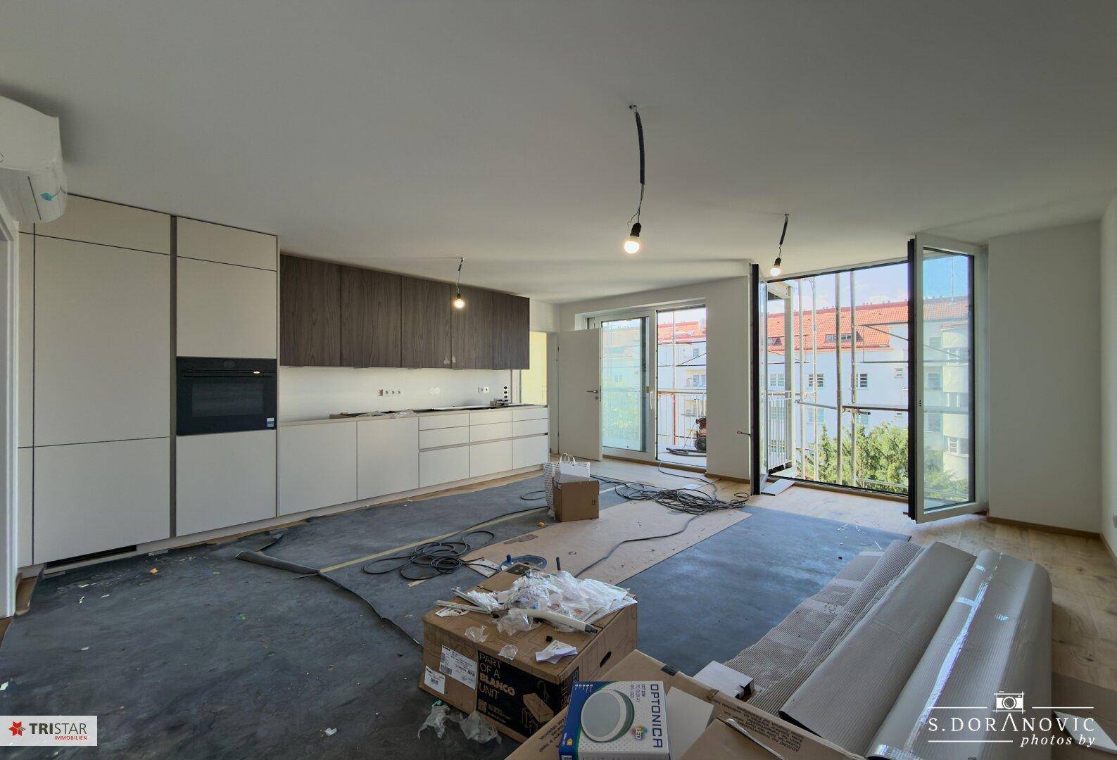 Küche im Bau mit modernen Einbauschränken und Blick auf den Außenbereich, noch in der Renovierungsphase.