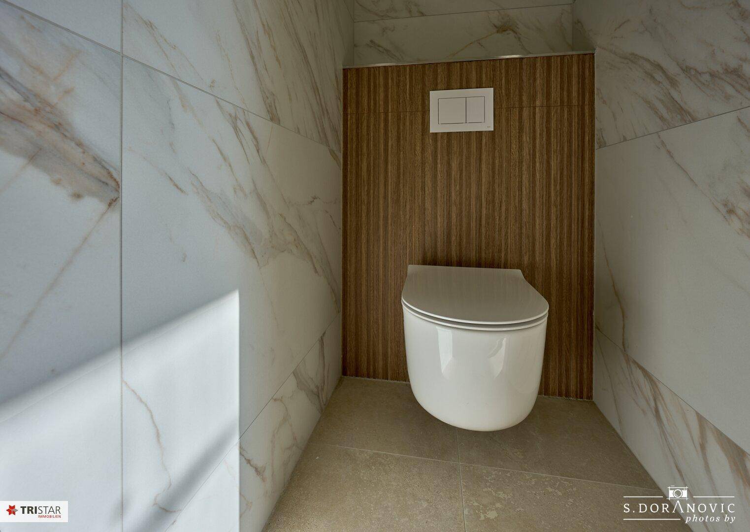 Modernes WC mit Wand-WC und eleganten Marmorfliesen, noch im Bau.