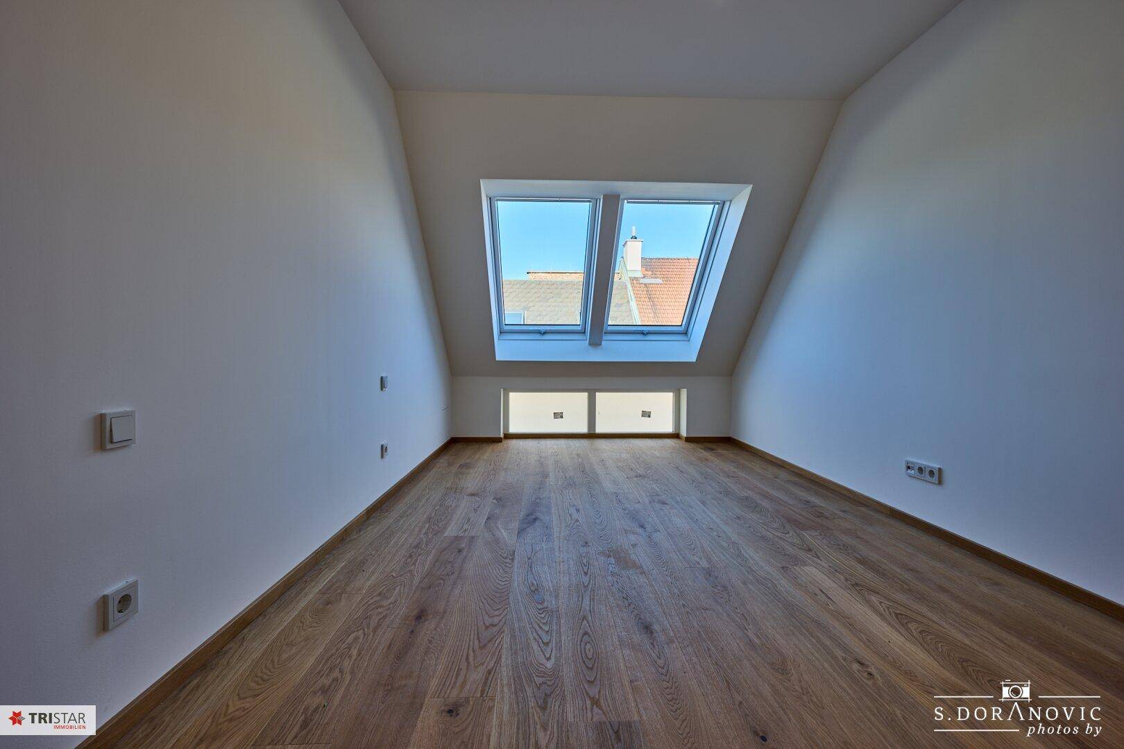 Gemütliches Schlafzimmer im Dachgeschoss mit Holzboden und Dachfenstern für viel Licht.