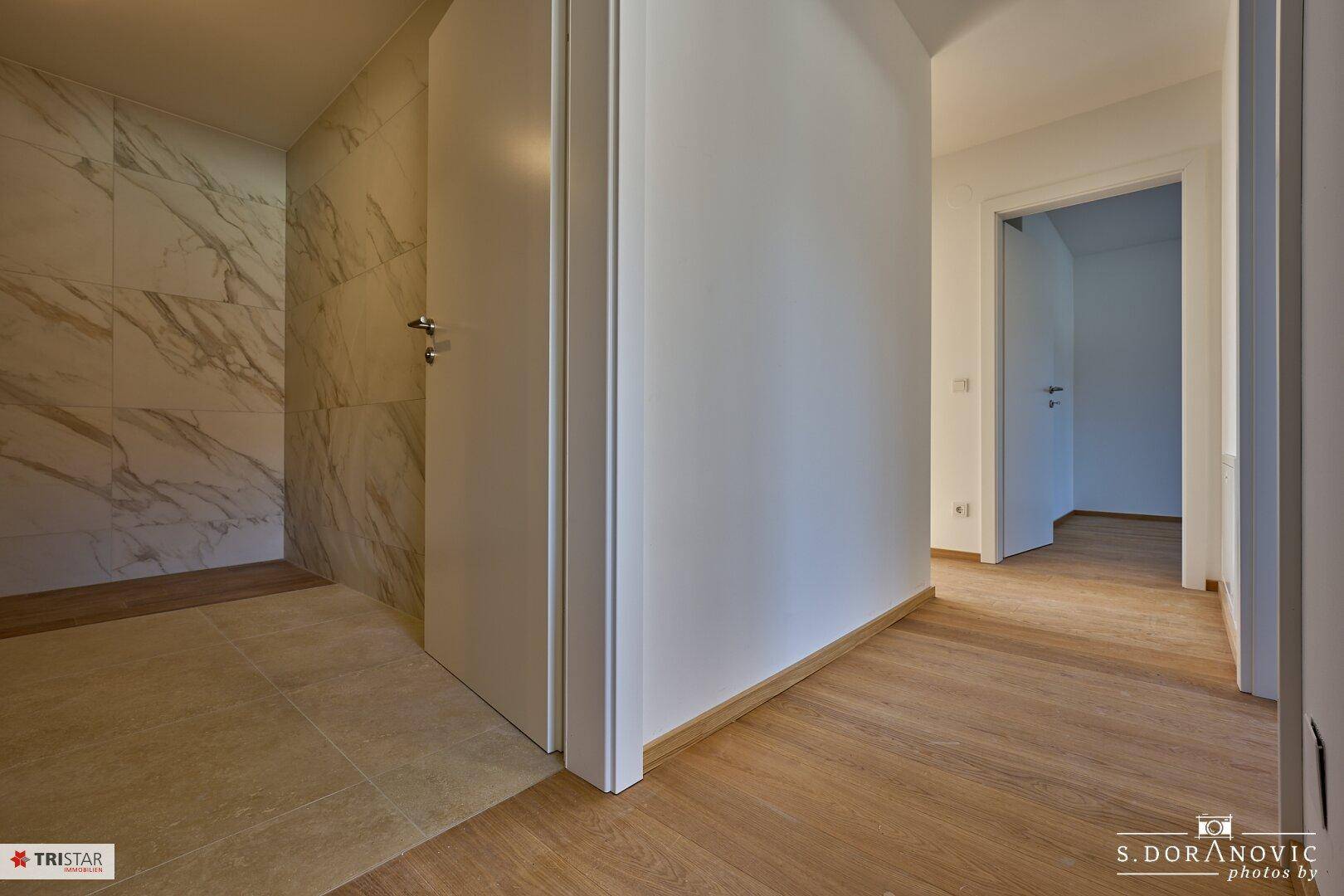 Heller Flur mit Holzboden und Zugang zu verschiedenen Räumen, noch im Bau.