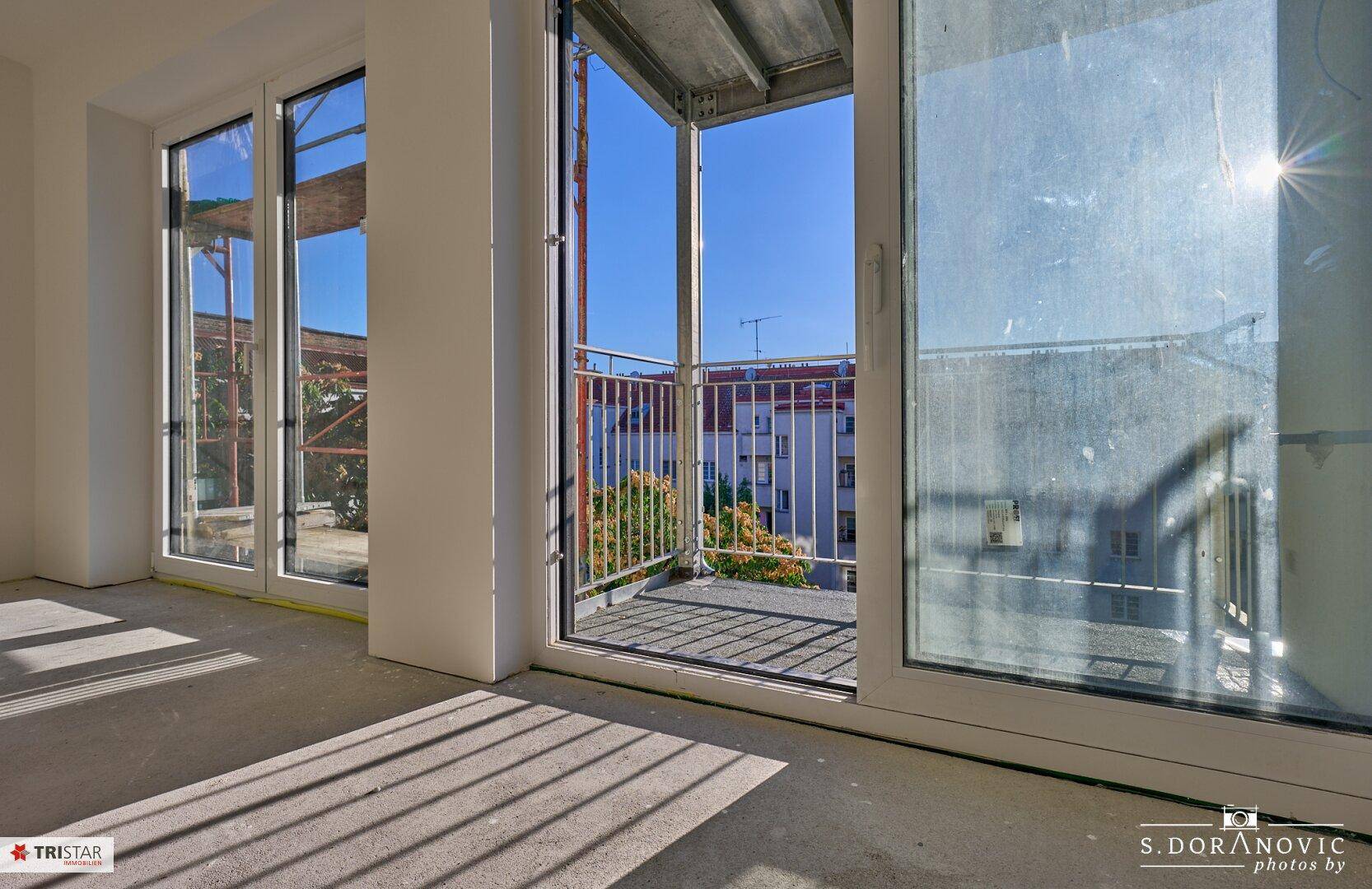 Helle Innenecke mit Zugang zu einem Balkon, der noch im Bau ist und viel Sonnenlicht hereinlässt.