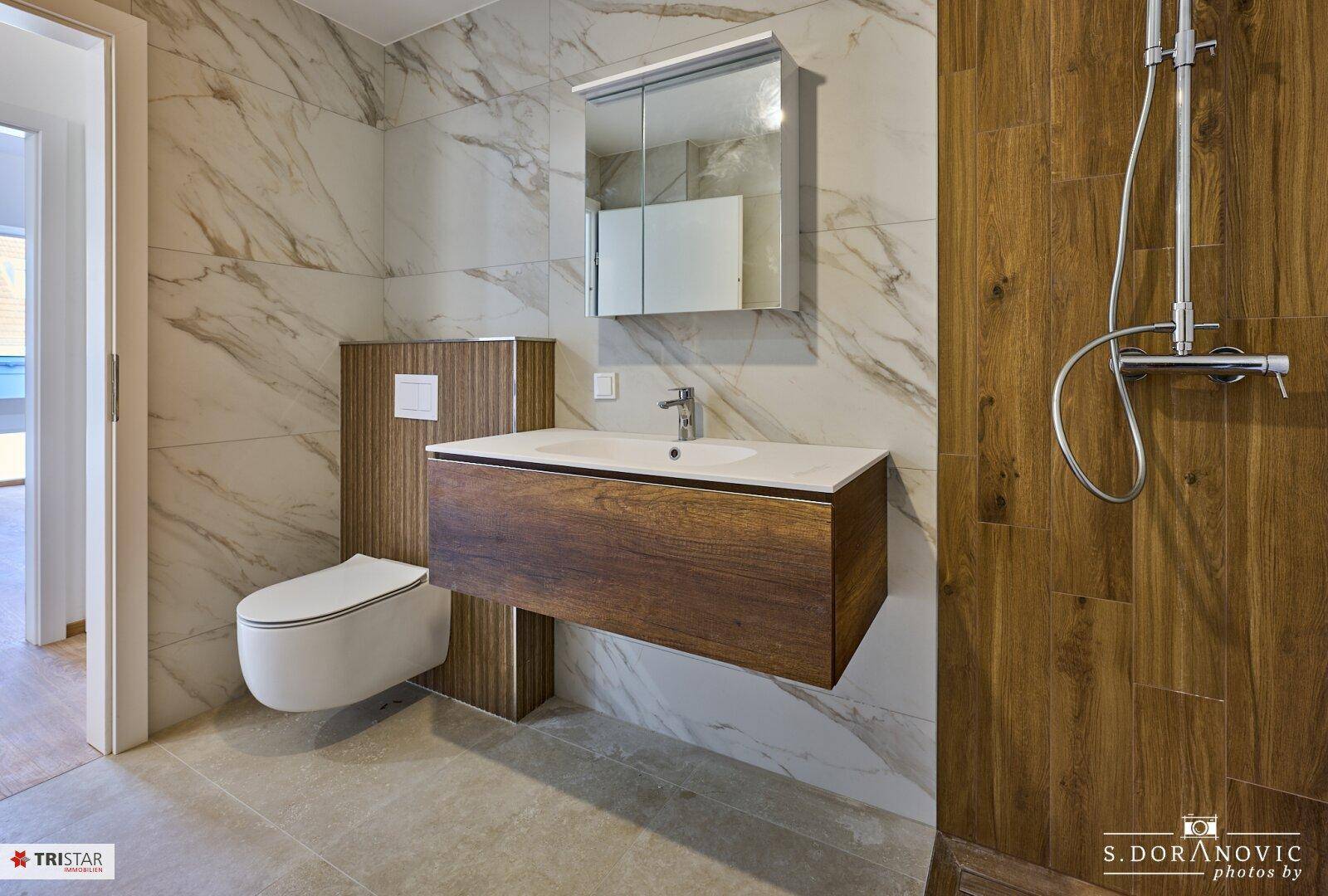 Elegantes Badezimmer mit schwebendem Holzwaschtisch, Wand-WC und großformatigen Marmorfliesen.