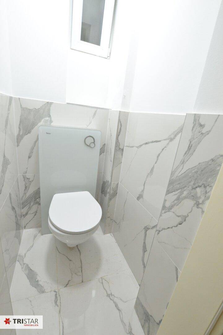 Separates WC mit modernen Marmorfliesen und wandhängender Toilette.
