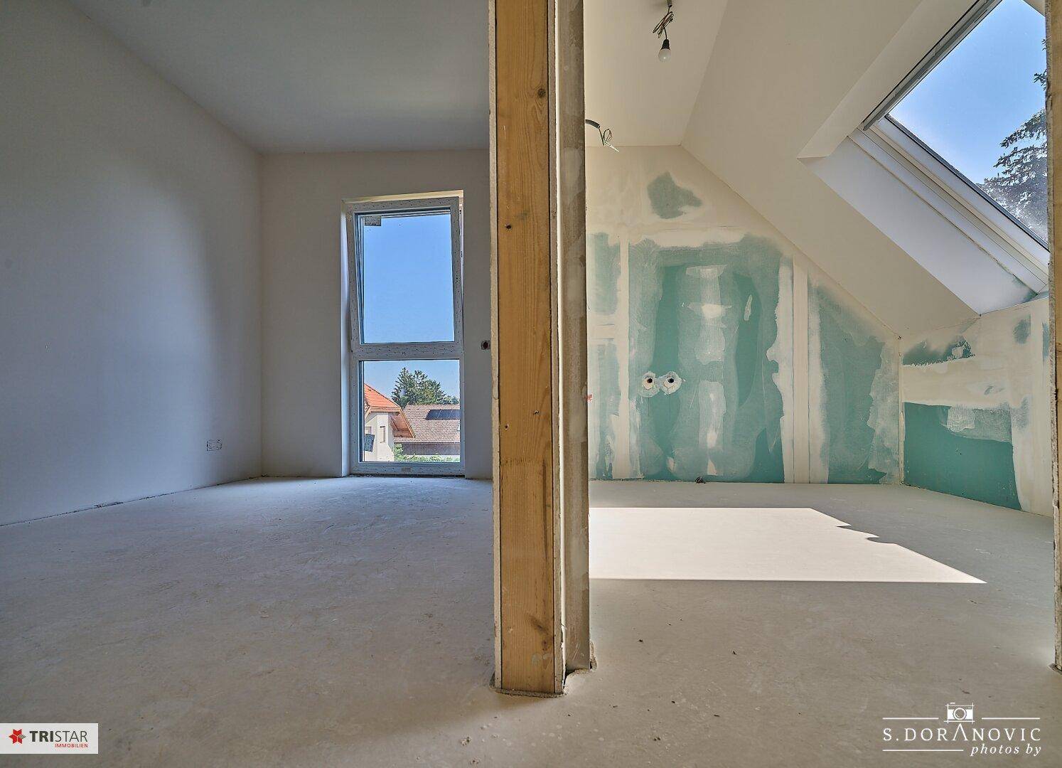Geräumiger Dachbodenraum im Rohbau mit Dachschräge und einem großen Dachfenster.