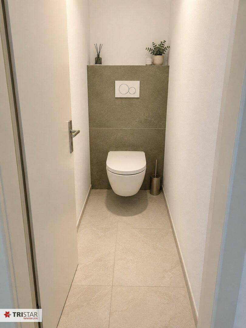 Separates Gäste-WC mit wandhängender Toilette und modernen grauen Fliesen, minimalistisch gestaltet.