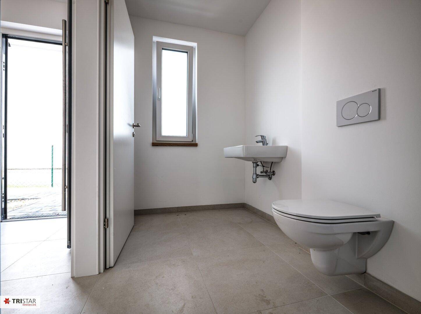 Modernes Gäste-WC mit wandhängendem WC, Waschbecken und Fenster für Tageslicht.