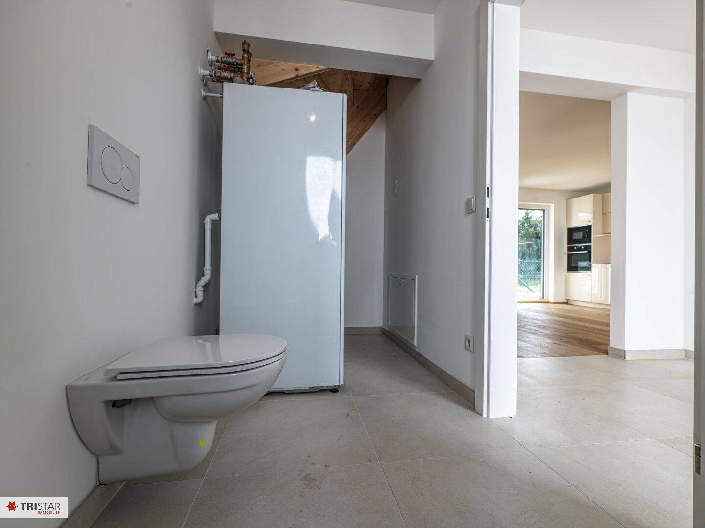 Gäste-WC mit wandhängender Toilette und Blick in den angrenzenden Wohnbereich.