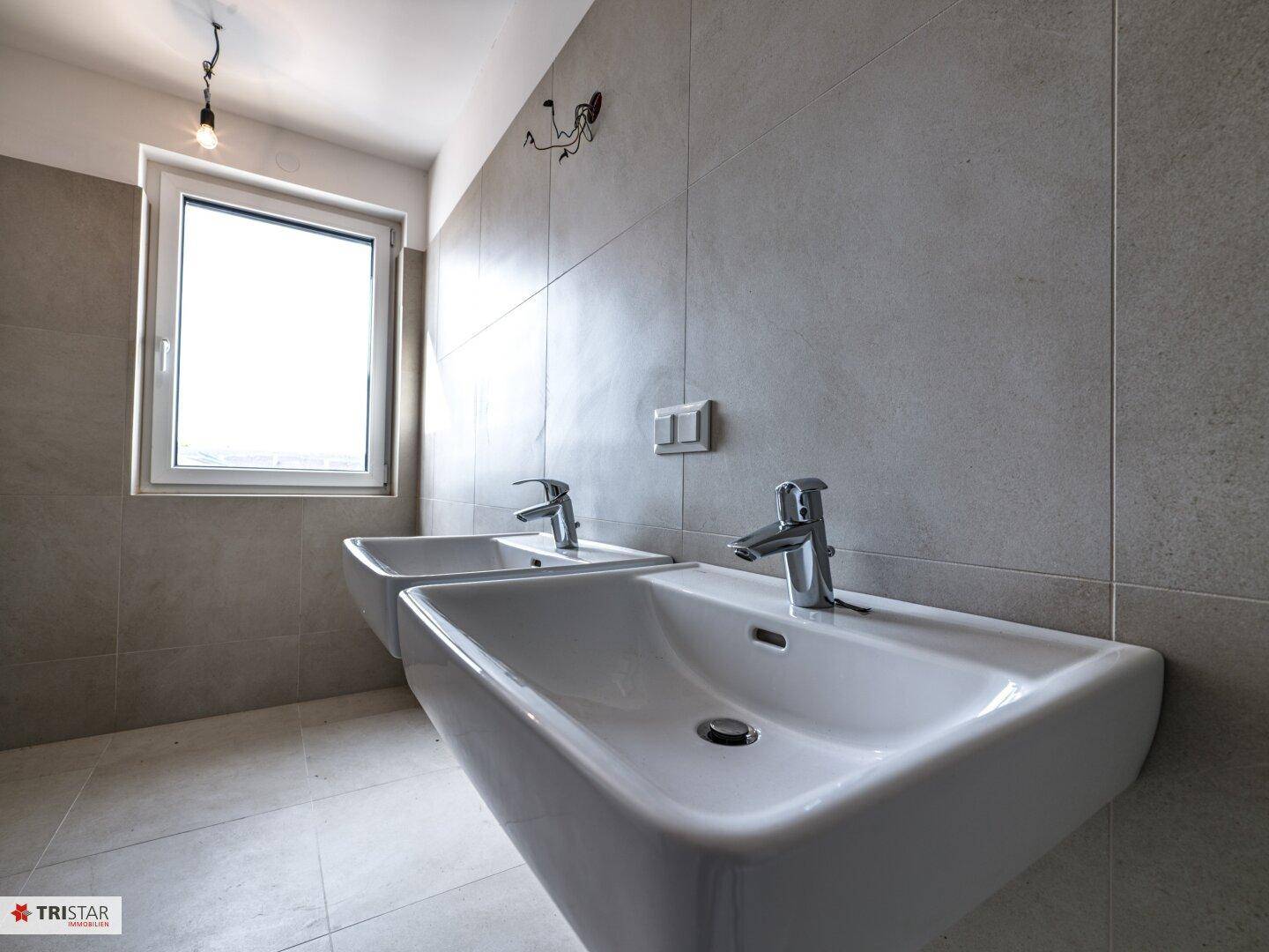 Detailansicht der modernen Doppelwaschbecken mit Chromarmaturen in einem hellen Badezimmer.