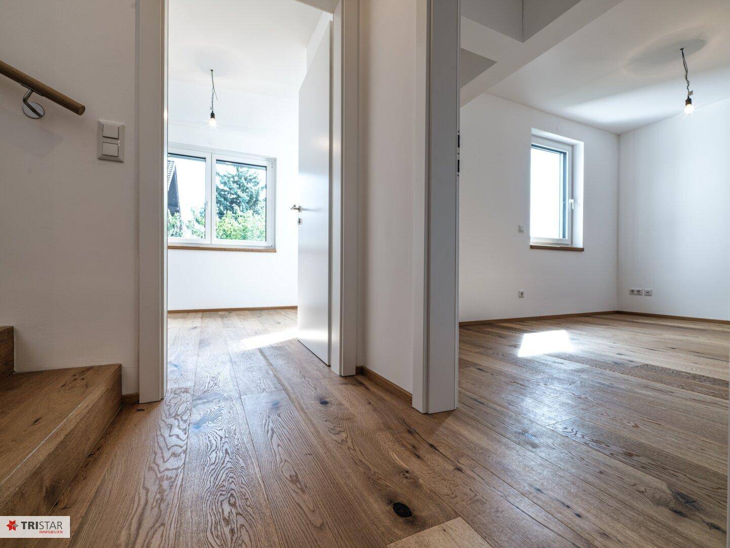 Heller Flur mit Holzboden, der zu verschiedenen Zimmern und einer Treppe führt.