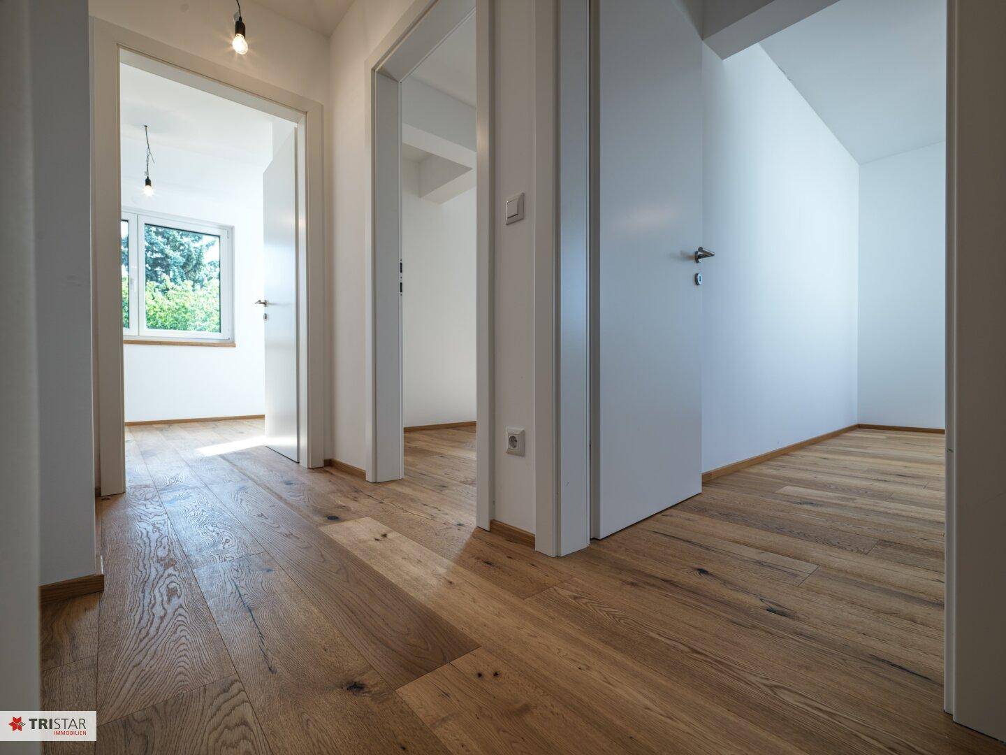 Geräumiger Flur mit Holzboden und mehreren Türen, die zu den angrenzenden Zimmern führen.