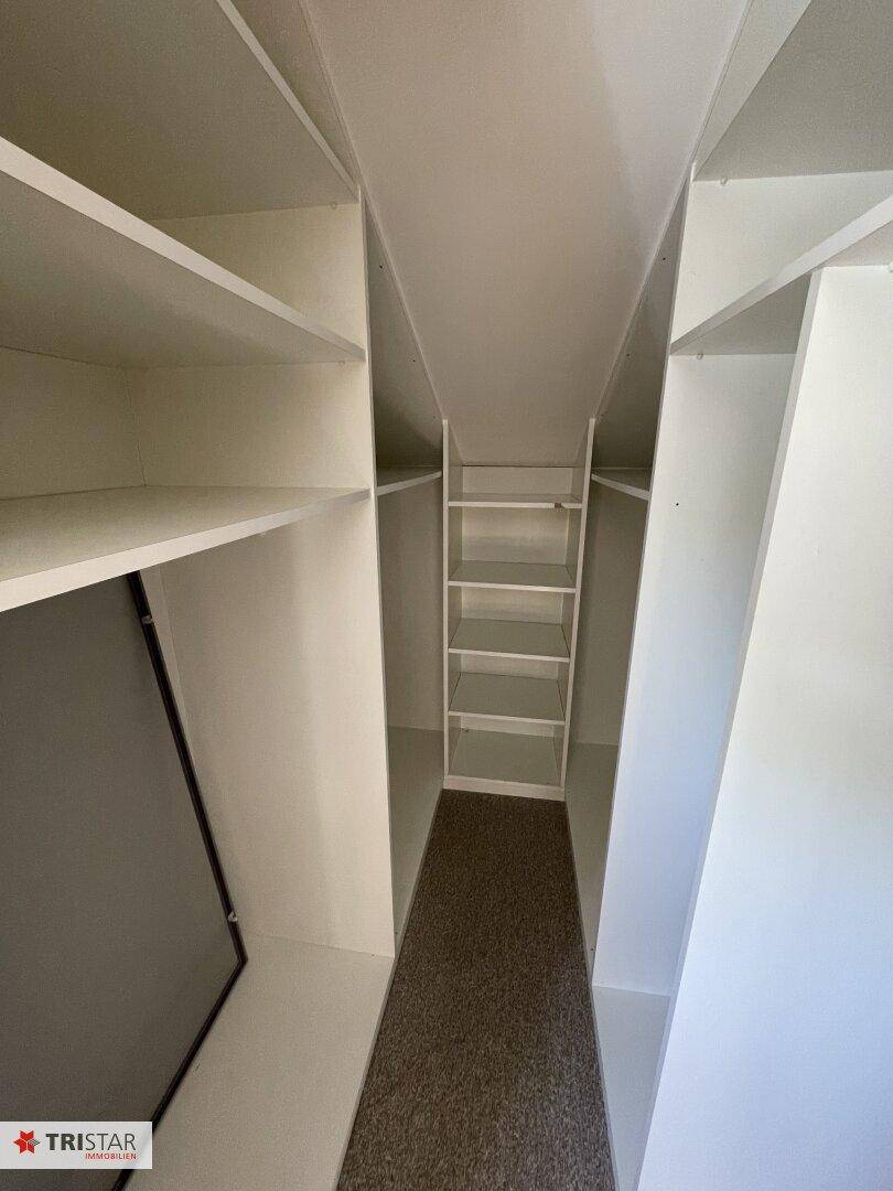 Praktischer Abstellraum mit vielen Regalen und Teppichboden für zusätzlichen Stauraum.