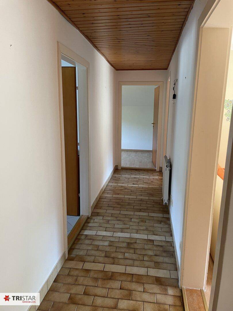 Langer Flur mit Holzdecke und Fliesenboden, der zu weiteren Räumen führt.