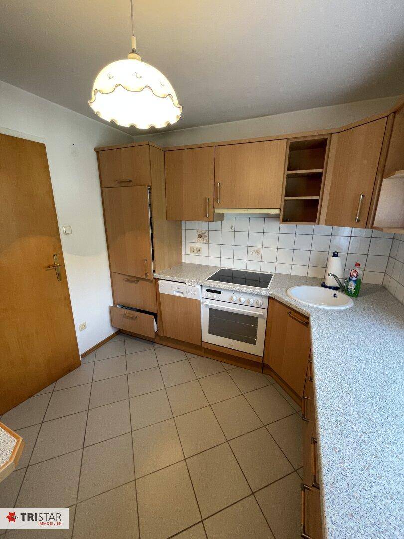 Funktionale Küche mit Holzfronten, integrierten Geräten und Fliesenboden.