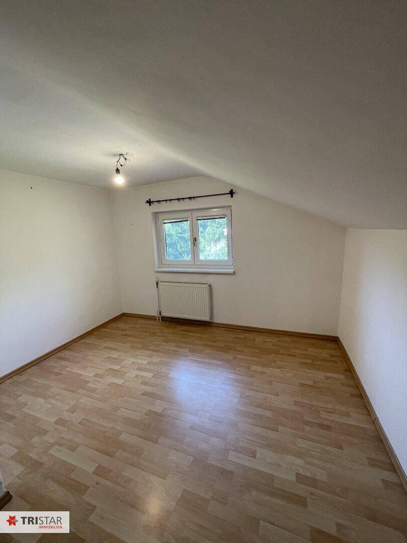 Helles Schlafzimmer im Dachgeschoss mit Laminatboden und Fenster.