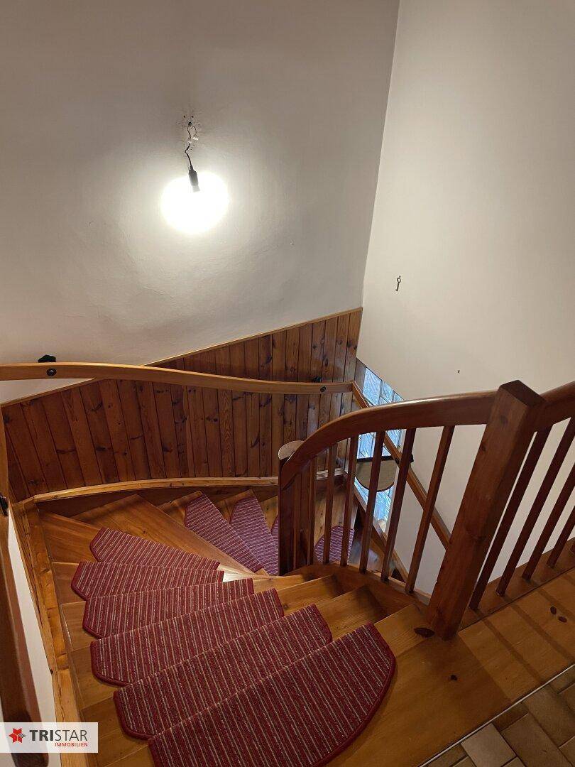Holztreppe mit Teppichläufern, die die verschiedenen Etagen des Hauses verbindet.