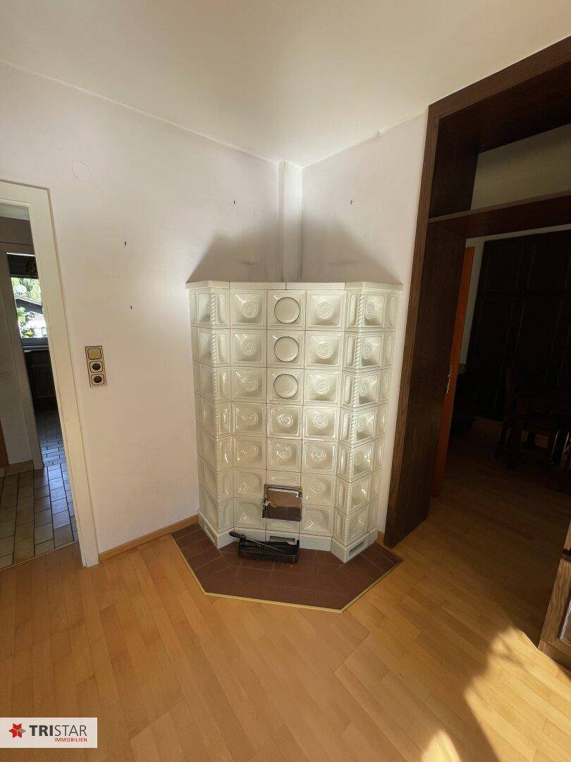 Gemütlicher Wohnbereich mit einem traditionellen Kachelofen und Holzboden.