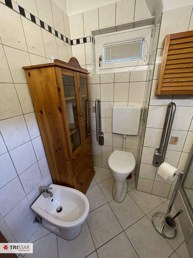 Badezimmer mit WC, Bidet, Waschbecken und Haltegriffen für zusätzliche Sicherheit.