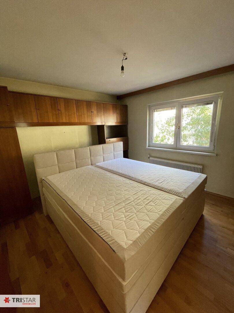 Helles Schlafzimmer mit Doppelbett, Holzboden und Einbauschränken.