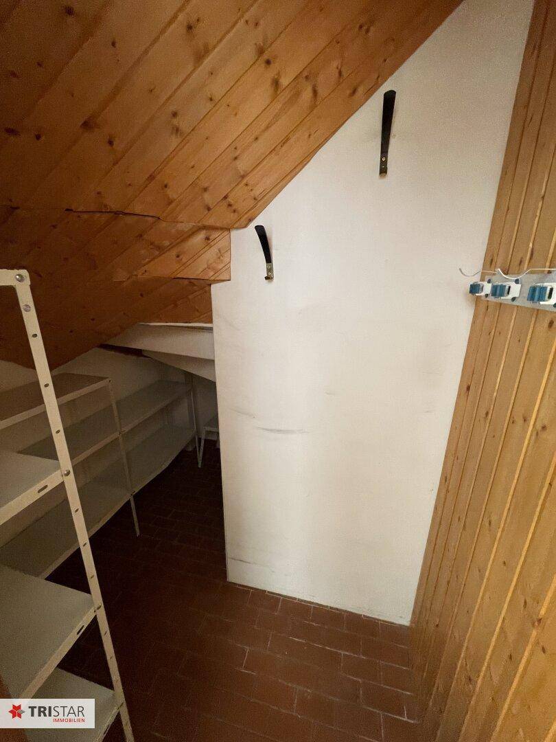Dachbodenraum mit Holzverkleidung und praktischen Regalen bietet zusätzlichen Stauraum unter der Dachschräge.