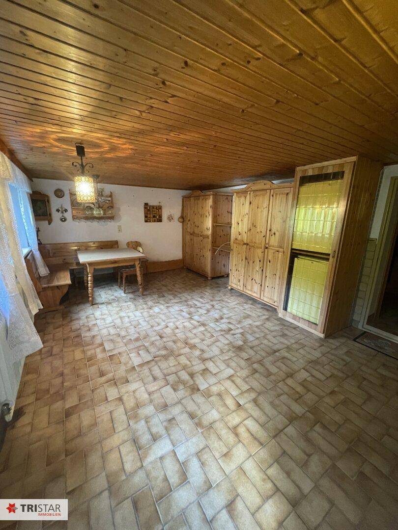 Rustikaler Wohnraum mit Holzwänden, Holzbalkendecke und Fliesenboden, ausgestattet mit traditionellen Holzmöbeln.