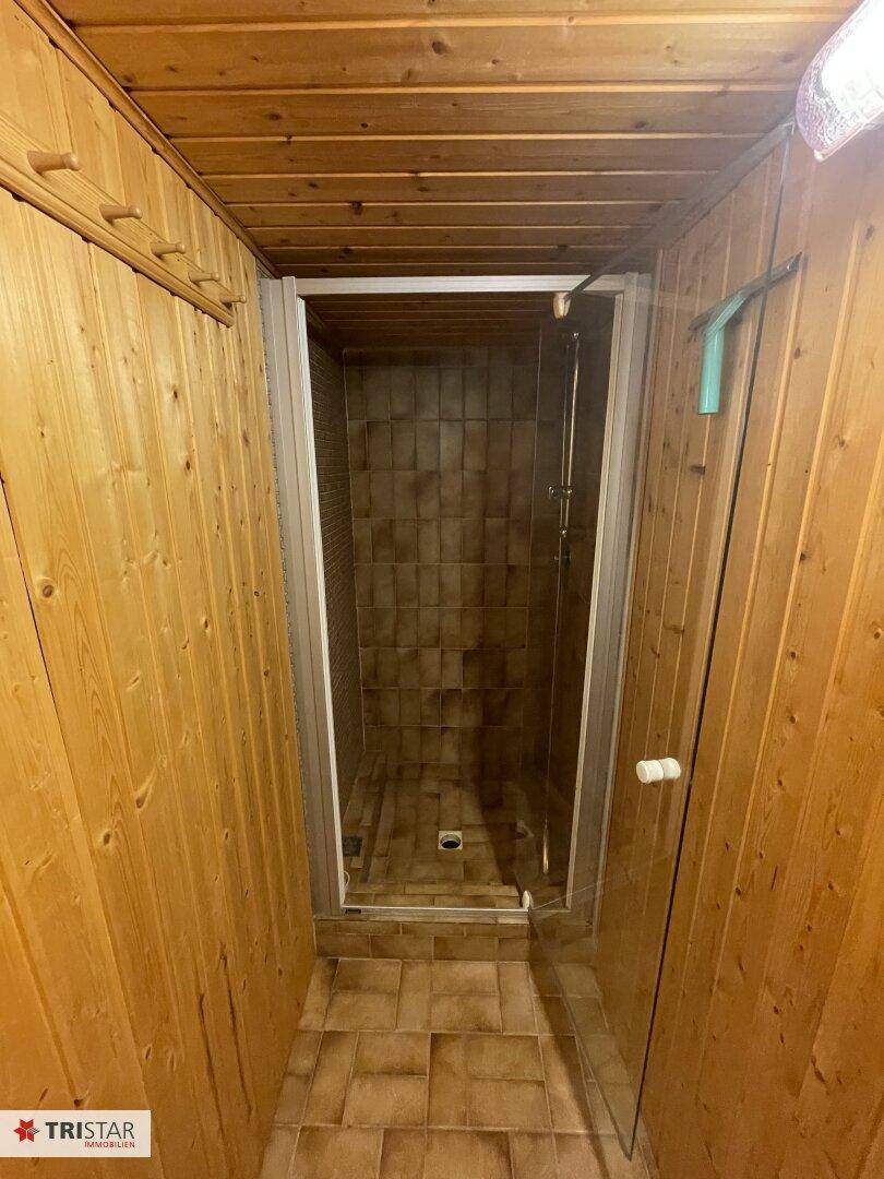 Kleines Badezimmer mit Duschkabine, Holzwänden und Fliesenboden im rustikalen Stil.