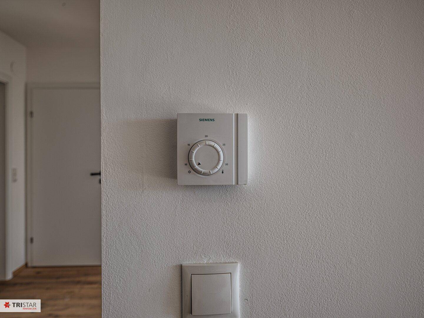 Siemens-Thermostat an einer weißen Wand, zur Steuerung der Raumtemperatur.