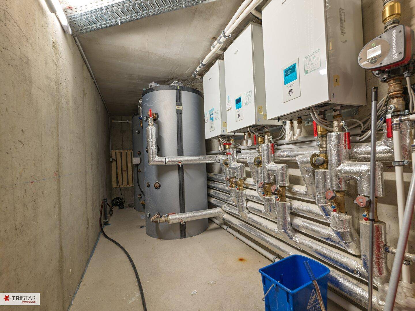 Technikraum mit Heizungsanlagen und Warmwasserspeichern im Untergeschoss des Gebäudes.