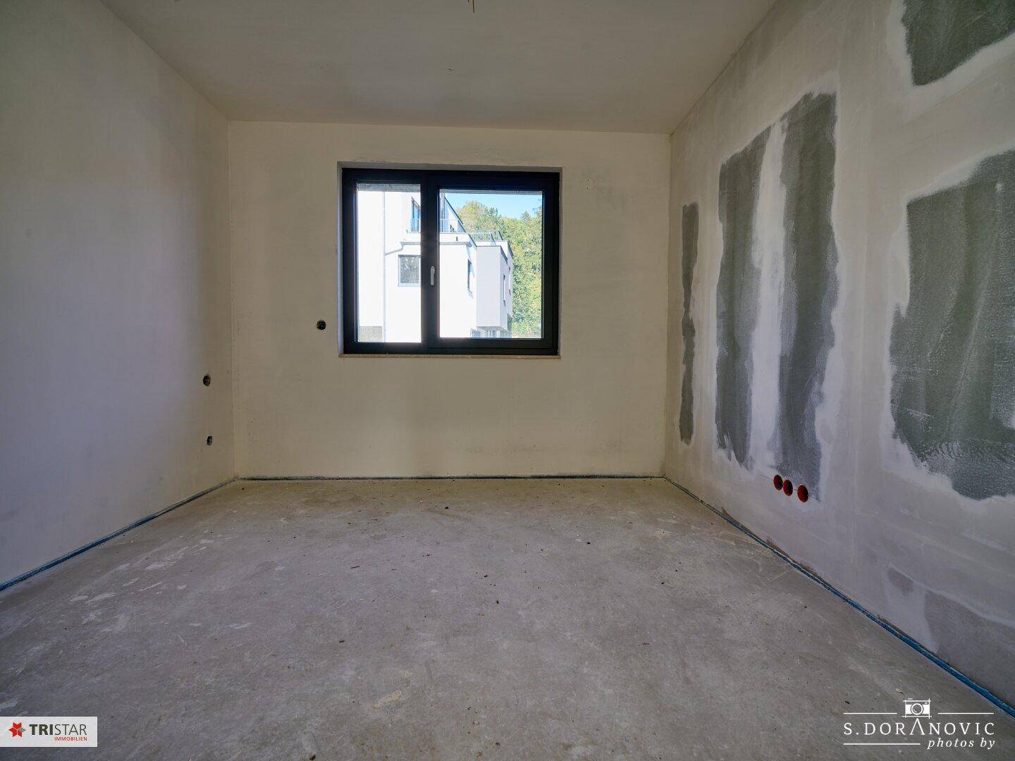 Unfertiges Schlafzimmer mit einem Fenster, das Tageslicht in den Raum bringt.