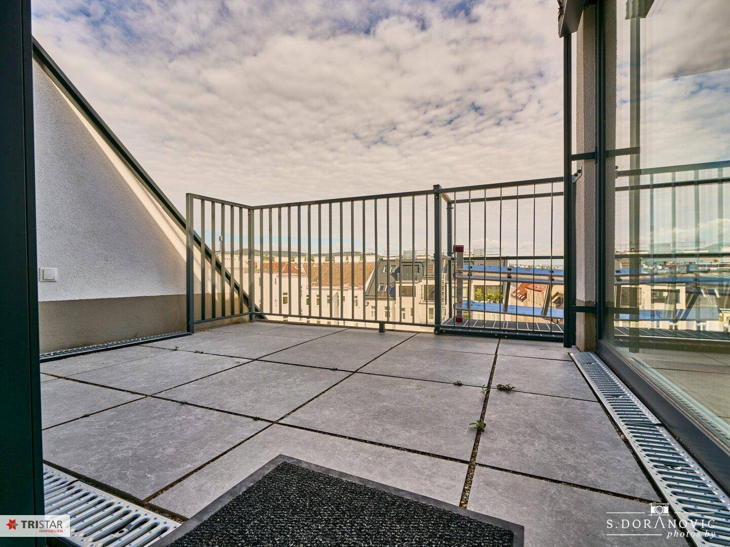 Geräumige Dachterrasse mit Fliesenboden und Metallgeländer, bietet weite Ausblicke.