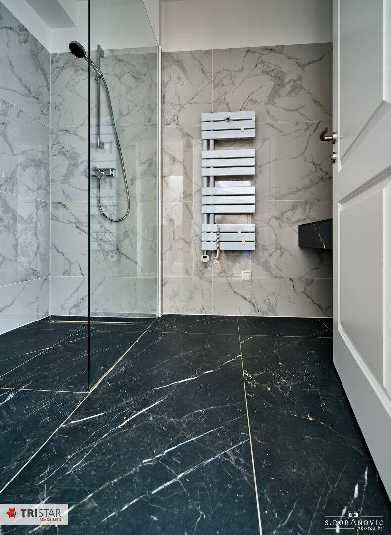 Modernes Badezimmer mit begehbarer Dusche, Marmorfliesen und beheiztem Handtuchhalter.