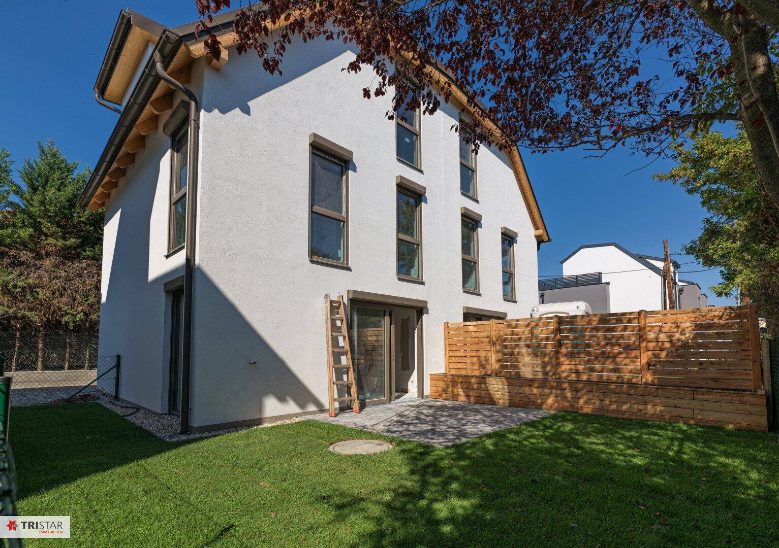 Ansicht des Hauses von der Gartenseite mit gepflasterter Terrasse und frisch angelegtem Rasen.