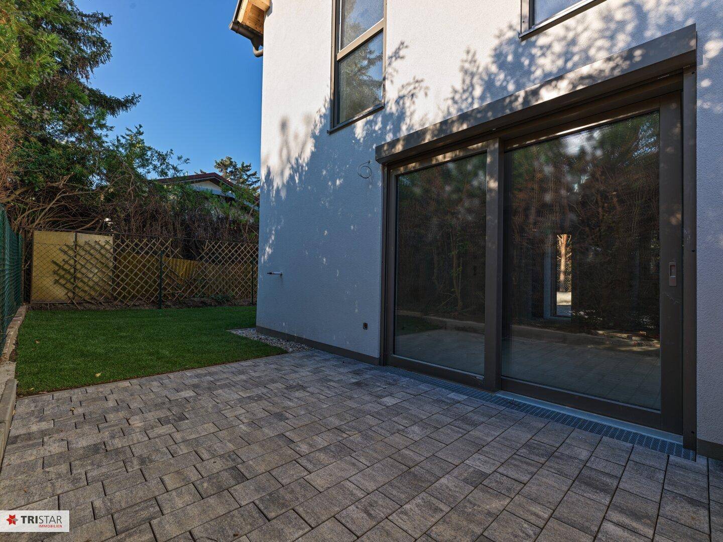 Detailansicht der gepflasterten Terrasse mit großer Glasschiebetür zum Innenbereich.