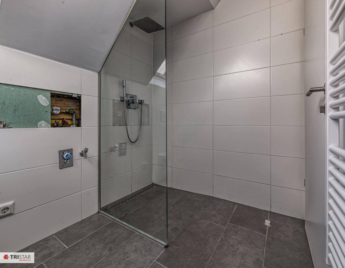 Modernes Badezimmer mit begehbarer Dusche, Glasabtrennung und beheiztem Handtuchhalter.