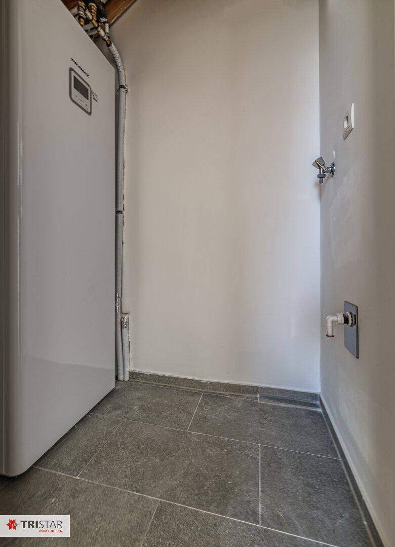 Funktionaler Hauswirtschaftsraum mit moderner Wärmepumpe und praktischem Fliesenboden.