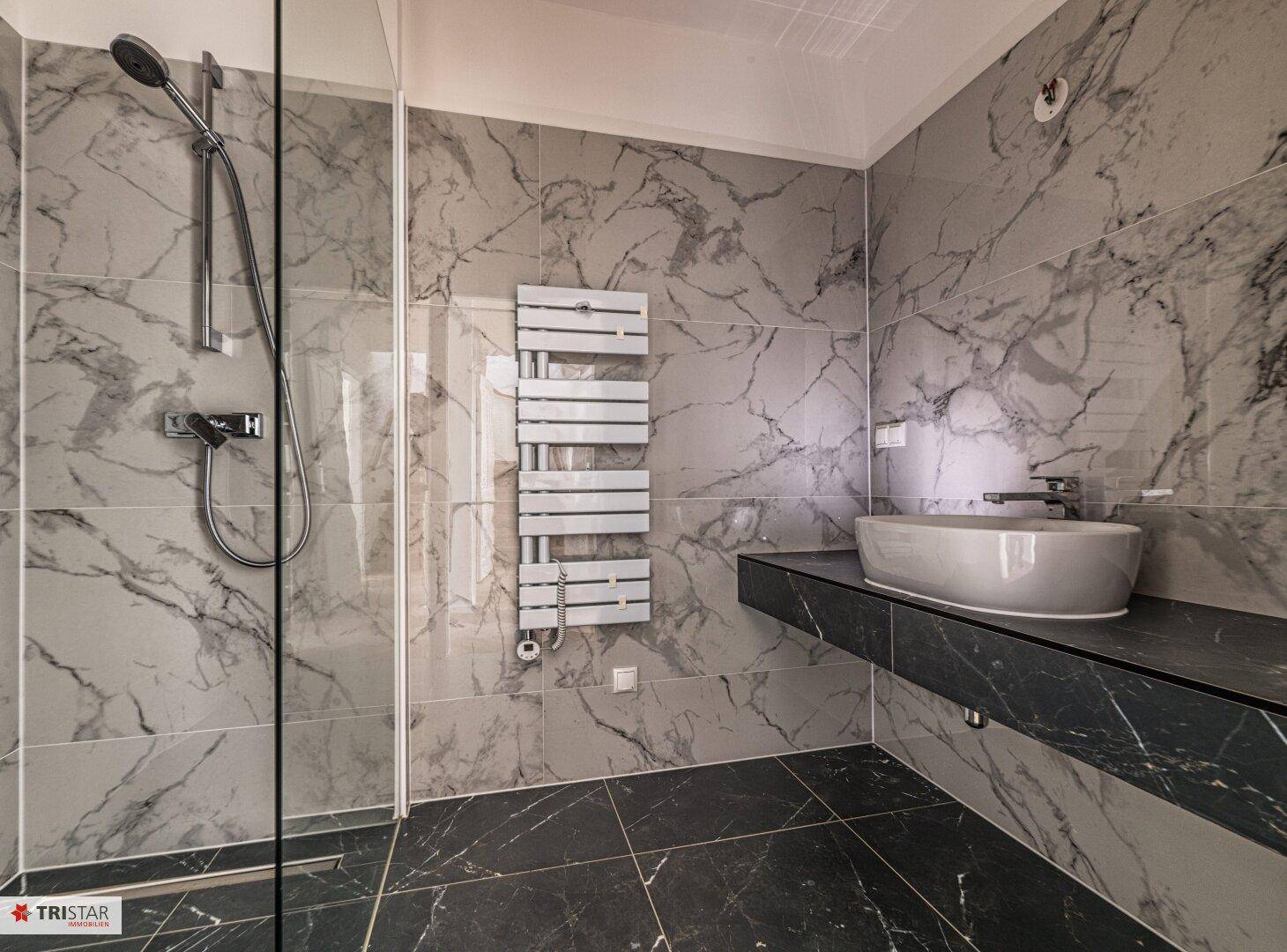 Modernes Badezimmer mit begehbarer Dusche, Waschtisch und Marmorfliesen in Grau und Schwarz.