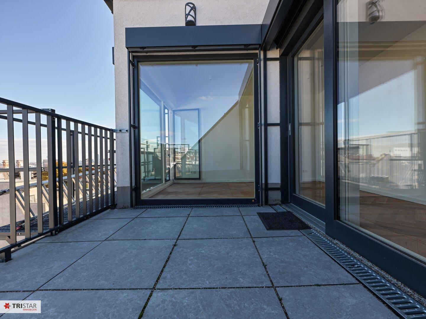 Geräumige Dachterrasse mit Fliesenboden und Zugang zu Innenräumen durch große Schiebetüren.