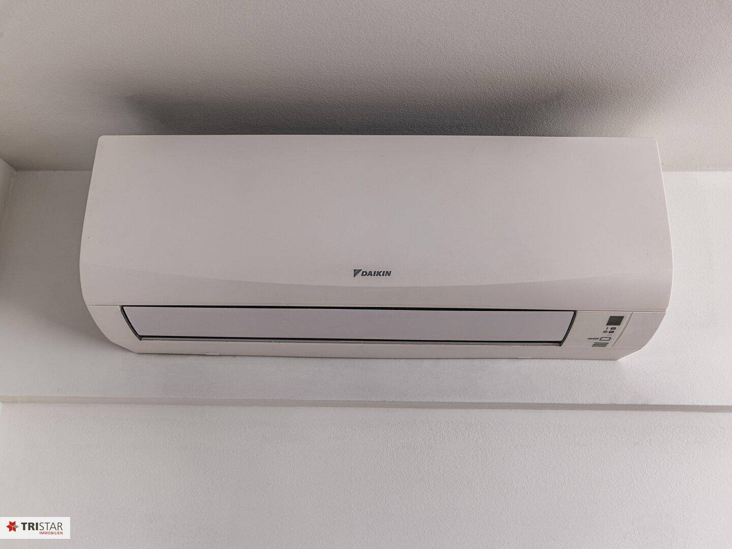 Eine moderne Klimaanlage der Marke Daikin an einer weißen Wand montiert.