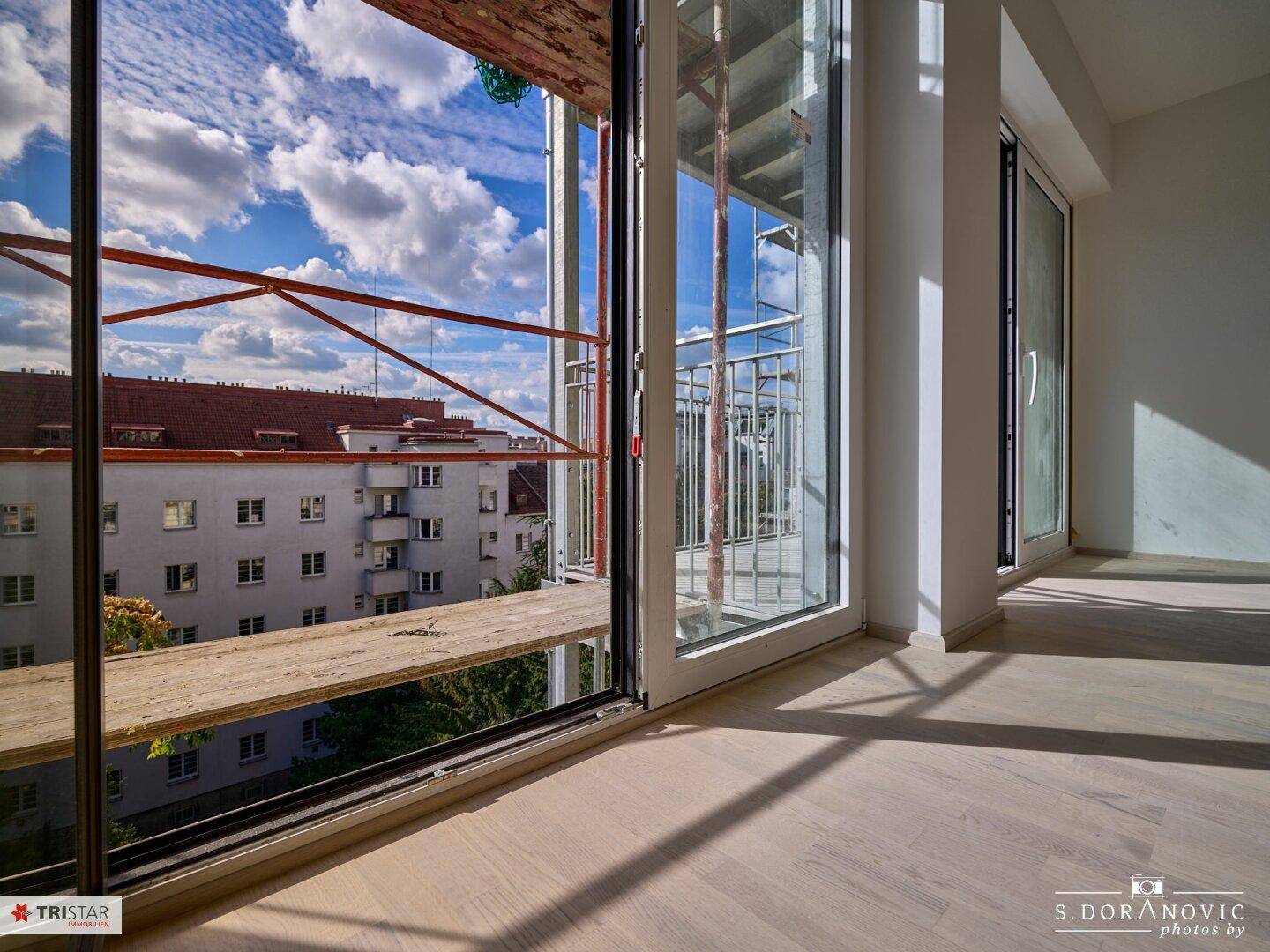 Große Fensterfront mit Blick auf die Umgebung und das Gerüst vor dem Gebäude.