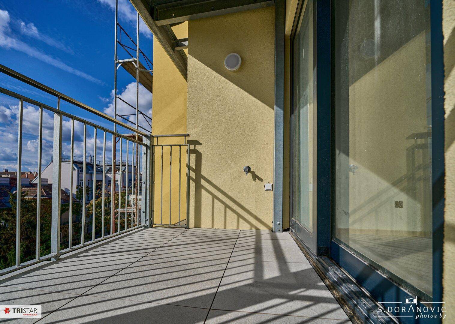 Geräumiger Balkon mit Fliesenboden und Metallgeländer, bietet einen Blick auf die Stadt.