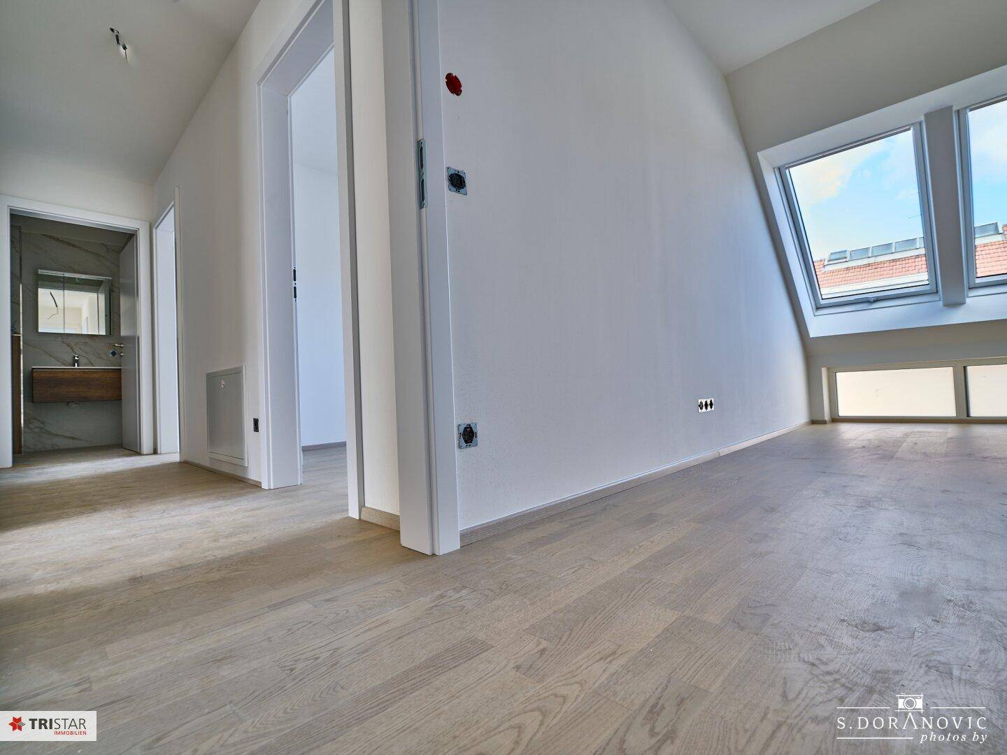 Flur im Dachgeschoss mit Holzboden, der zu einem Badezimmer und weiteren Räumen führt.