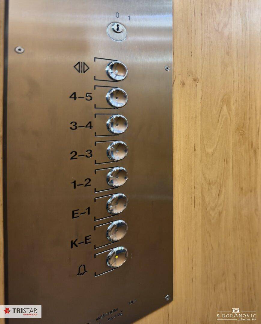 Bedienfeld eines Aufzugs mit Etagenknöpfen in einem Gebäude, aus gebürstetem Metall.