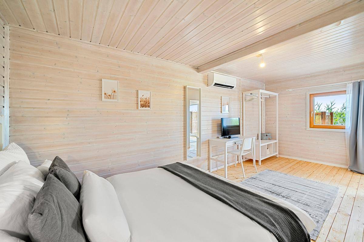 Helles Schlafzimmer mit komfortablem Bett, Holzvertäfelung und einem Fenster, das Tageslicht hereinlässt.