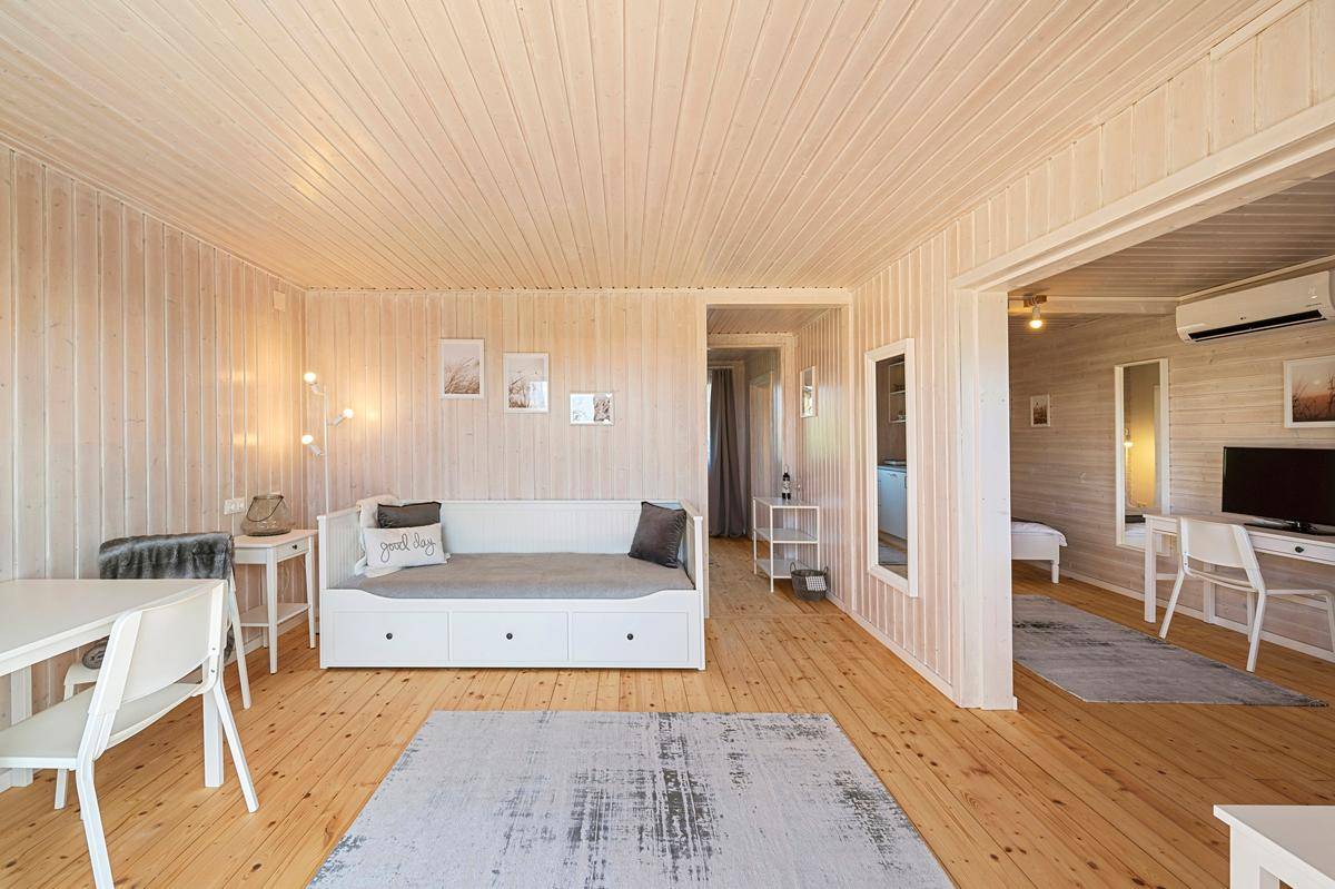 Offener Wohnbereich mit heller Holzvertäfelung, Tagesbett und Blick in angrenzende Räume.