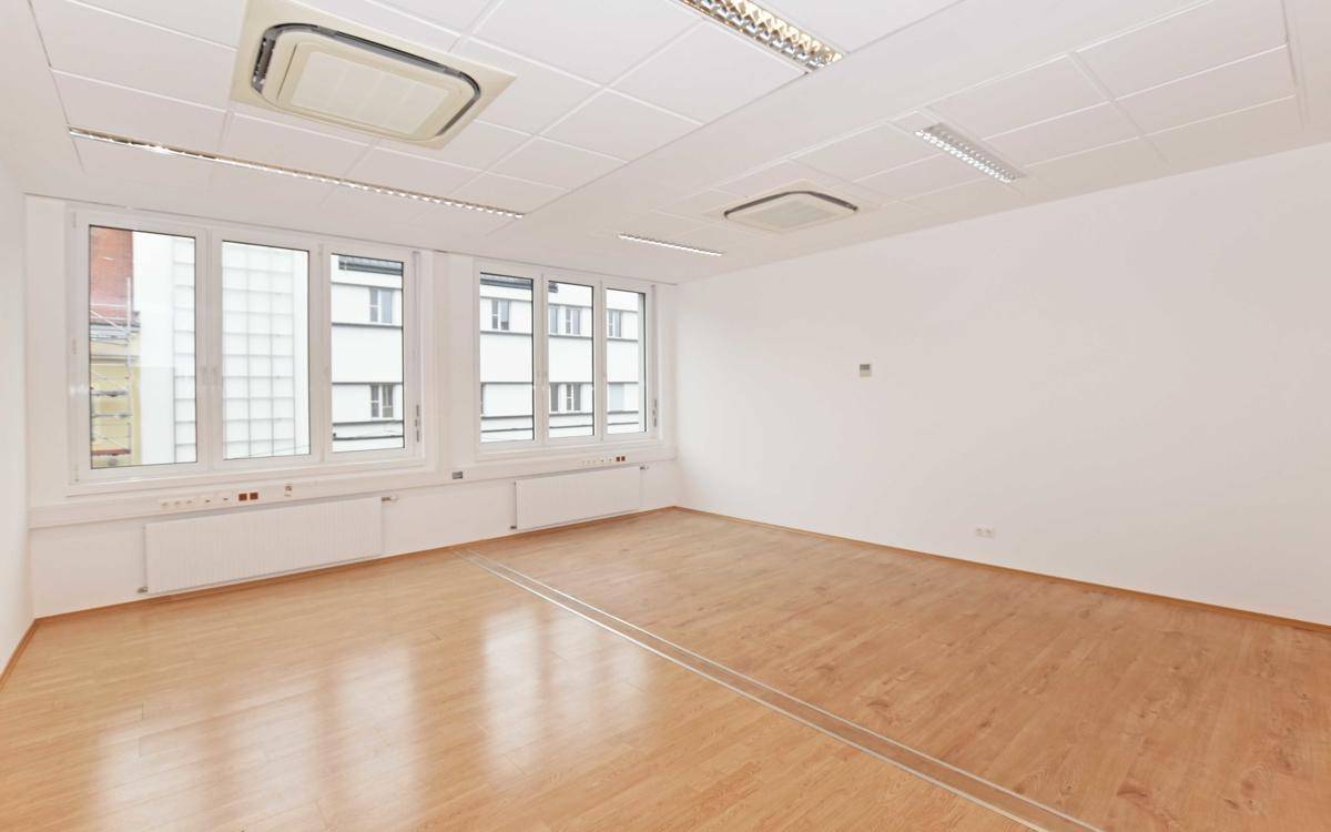 Modernes Büro mit zwei Klimaanlagen, hellen Wänden und Laminatboden, bietet eine angenehme Arbeitsumgebung.