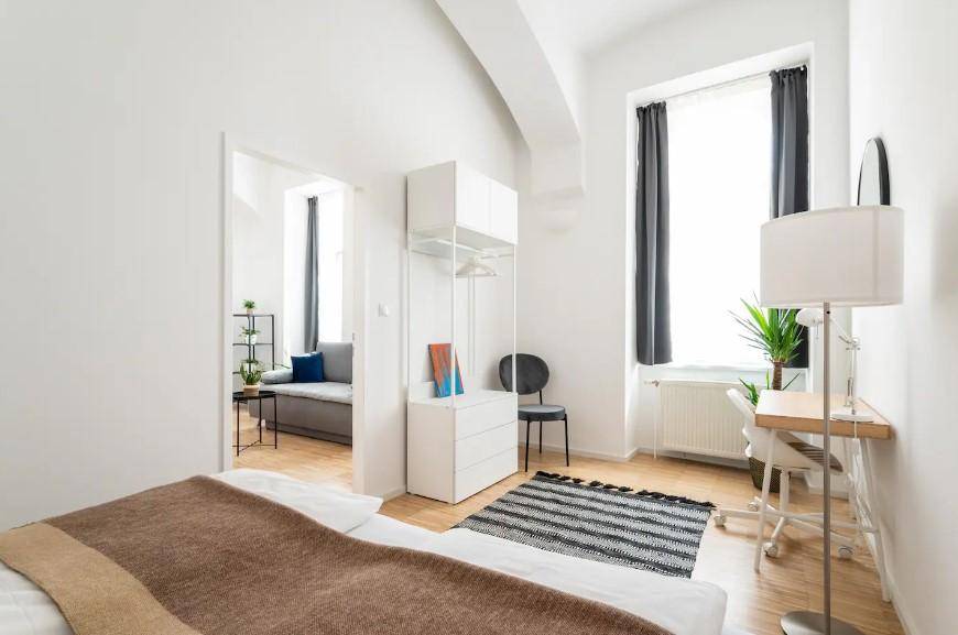 Schlafzimmer mit Blick auf den angrenzenden Wohnbereich, ausgestattet mit einem Schreibtisch und offenem Kleiderschrank.