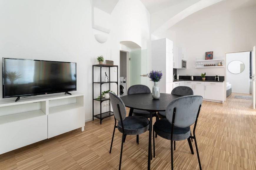 Kombinierter Wohn-, Ess- und Küchenbereich mit Fernseher, Esstisch und moderner Küchenzeile.